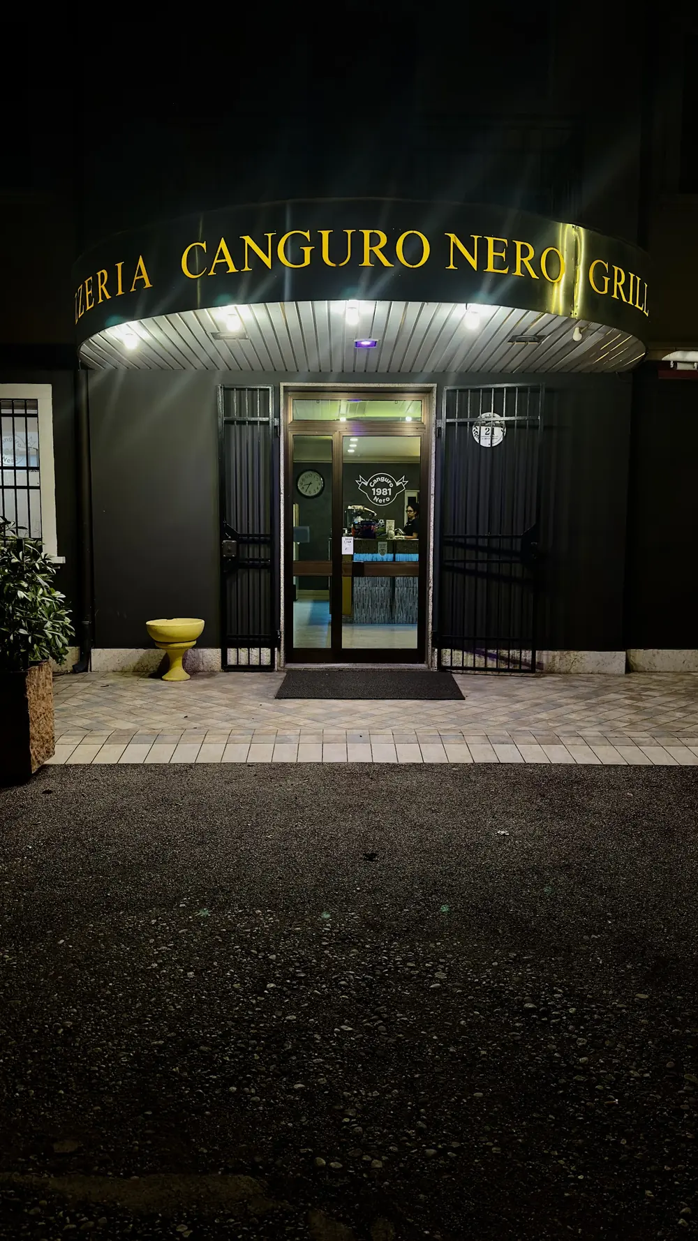 L'ingresso della Pizzeria Canguro Nero di sera, con l'insegna illuminata
